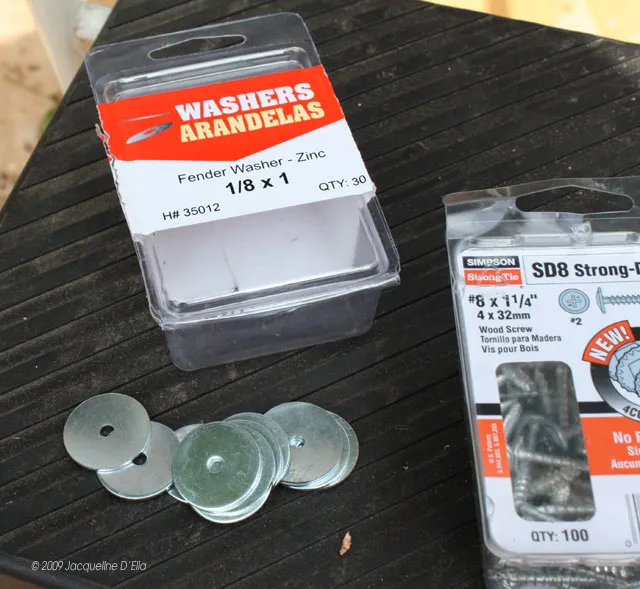 A vertical trellis holding a box of washers and screws on a table.